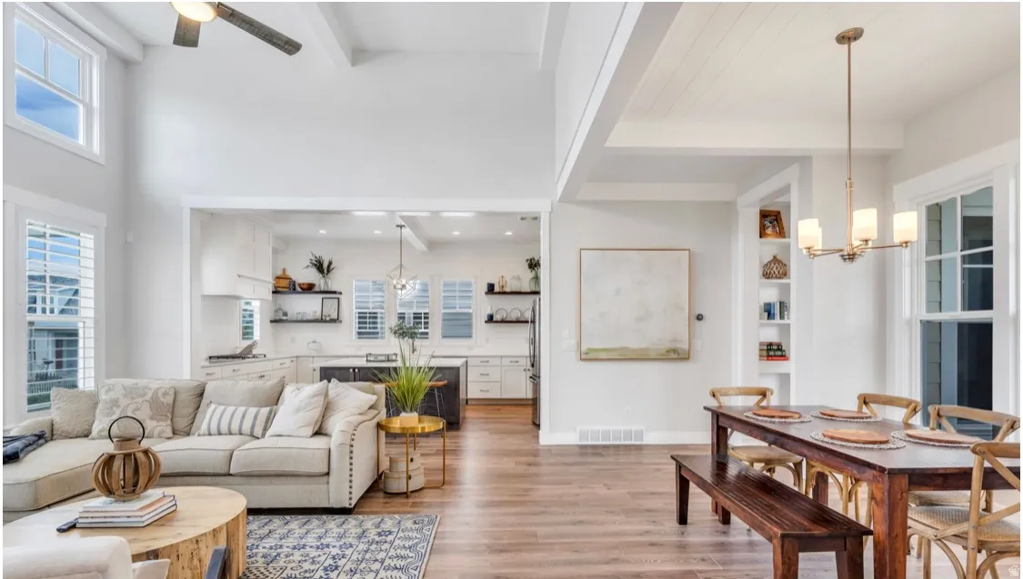 Open-concept living area featuring high ceilings, wood-finish flooring, a contemporary ceiling fan, and white plantation shutters