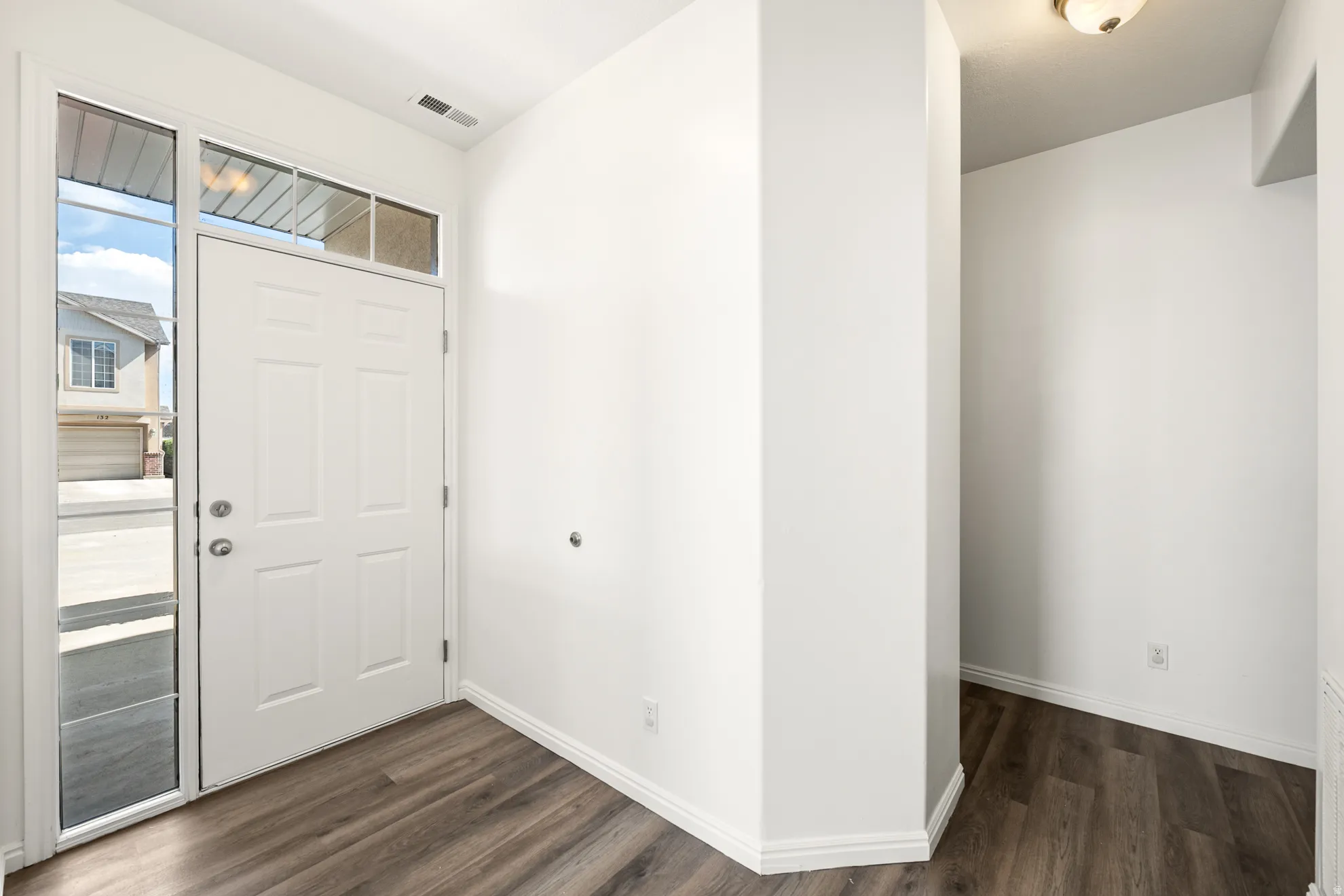 Entryway featuring a paneled door with sidelight and transom windows, wood-finish flooring, and white baseboards