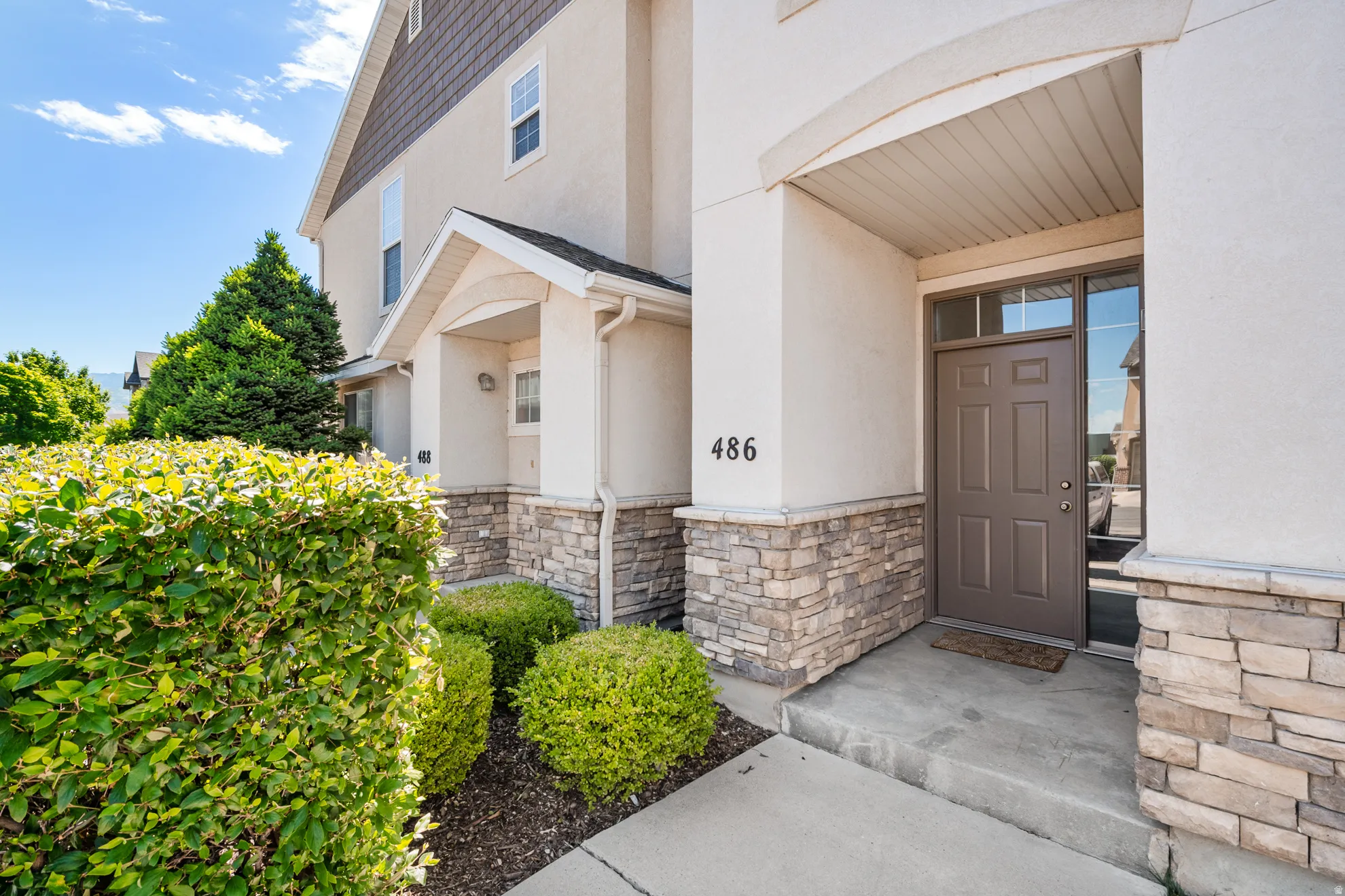 Stucco exterior featuring stacked stone accents and a covered entryway