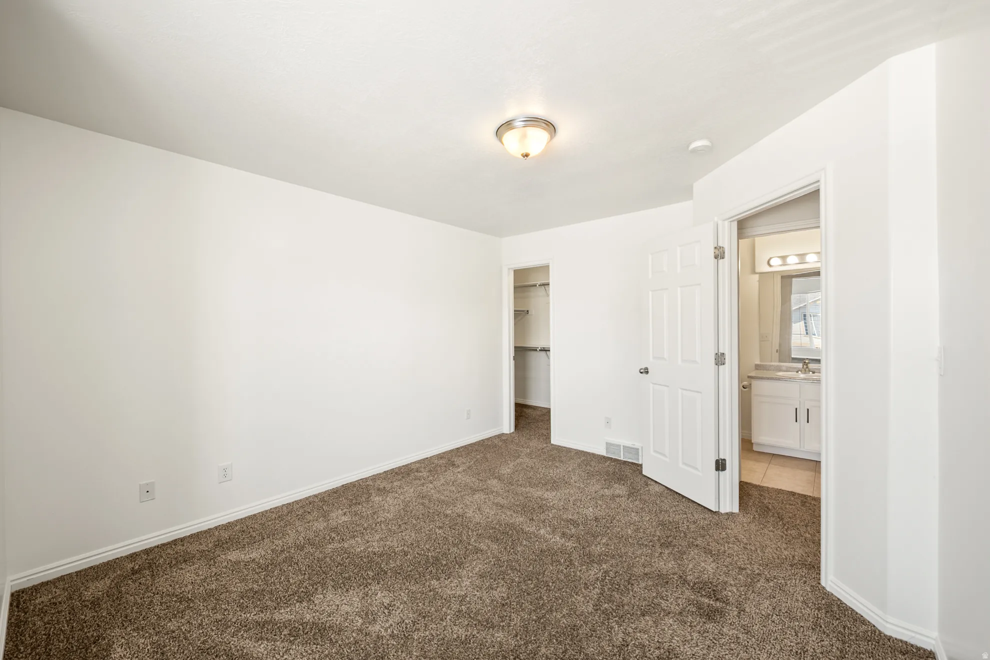 Carpeted room with white walls, a built-in closet with shelving, and an overhead light fixture