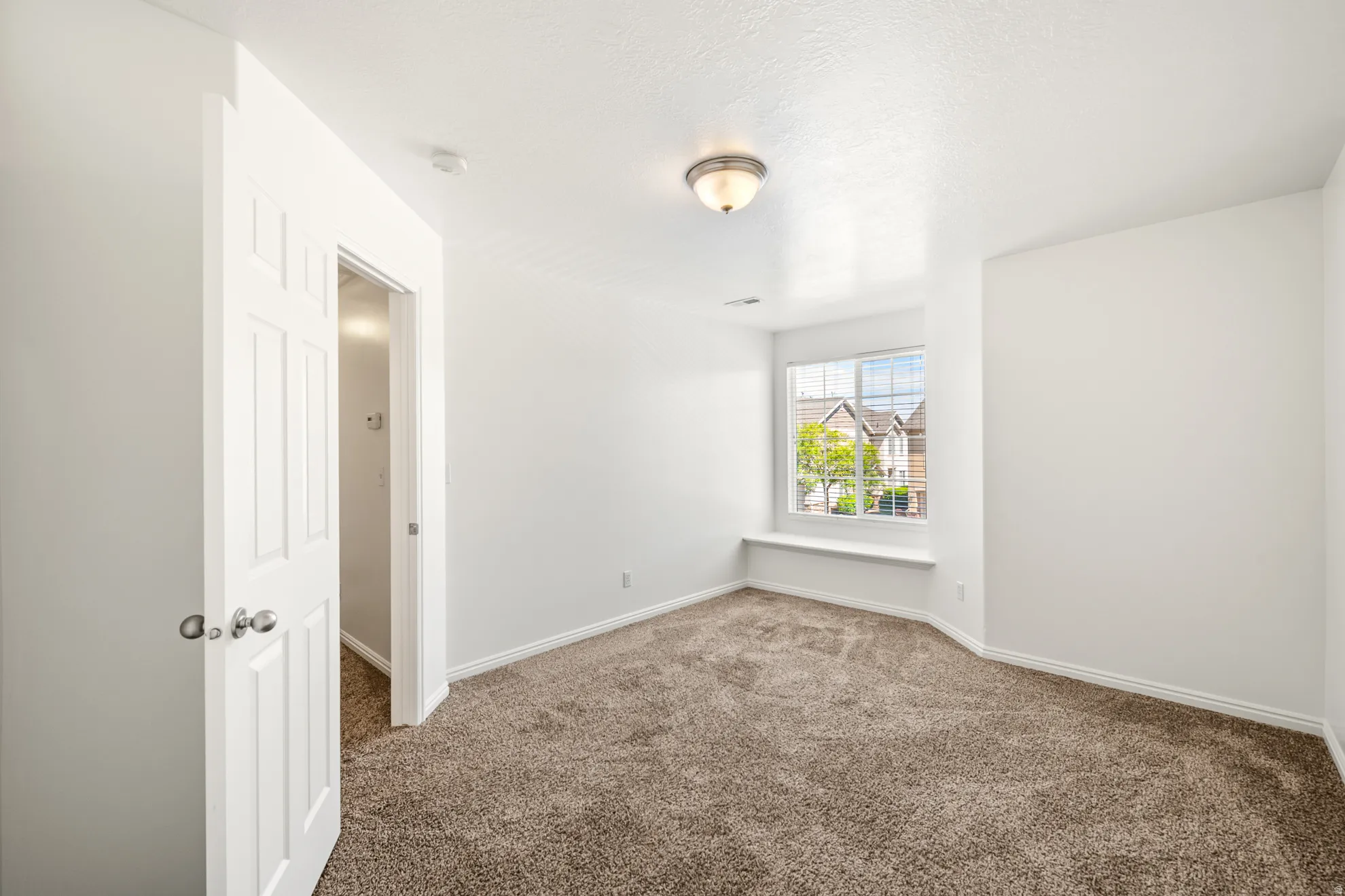 Carpeted room featuring a window with a built-in sill, white trim, and a semi-flush mount ceiling light