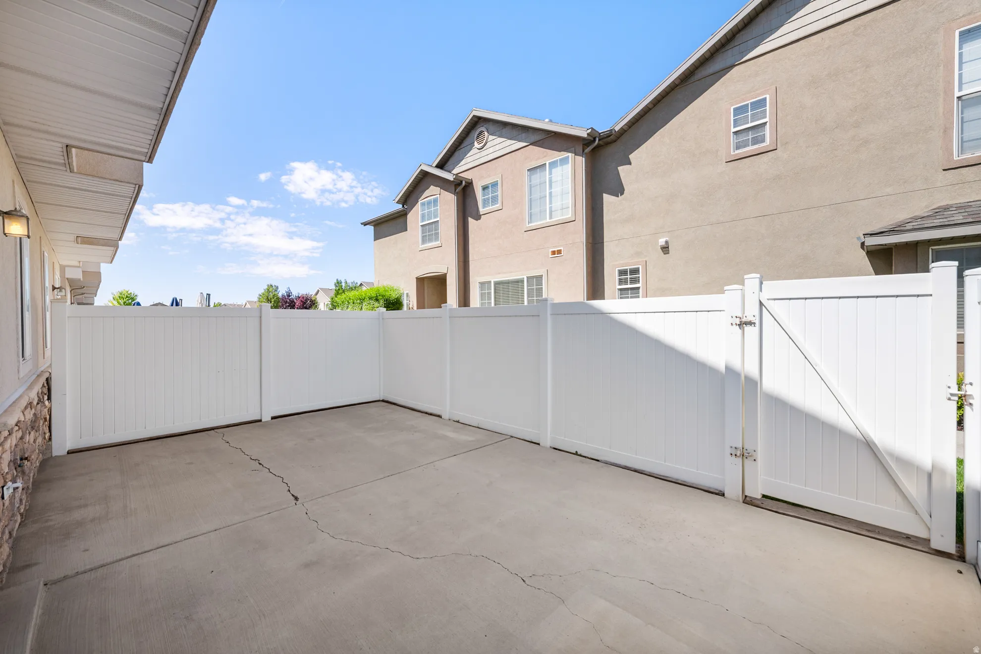 Private concrete patio area with white vinyl fencing and a matching gate