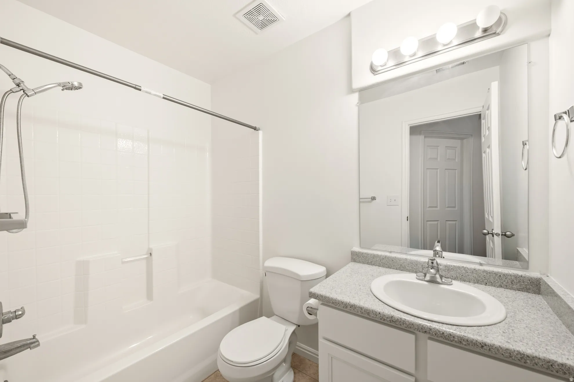 Bathroom with a white bathtub and shower combination featuring subway tile surround