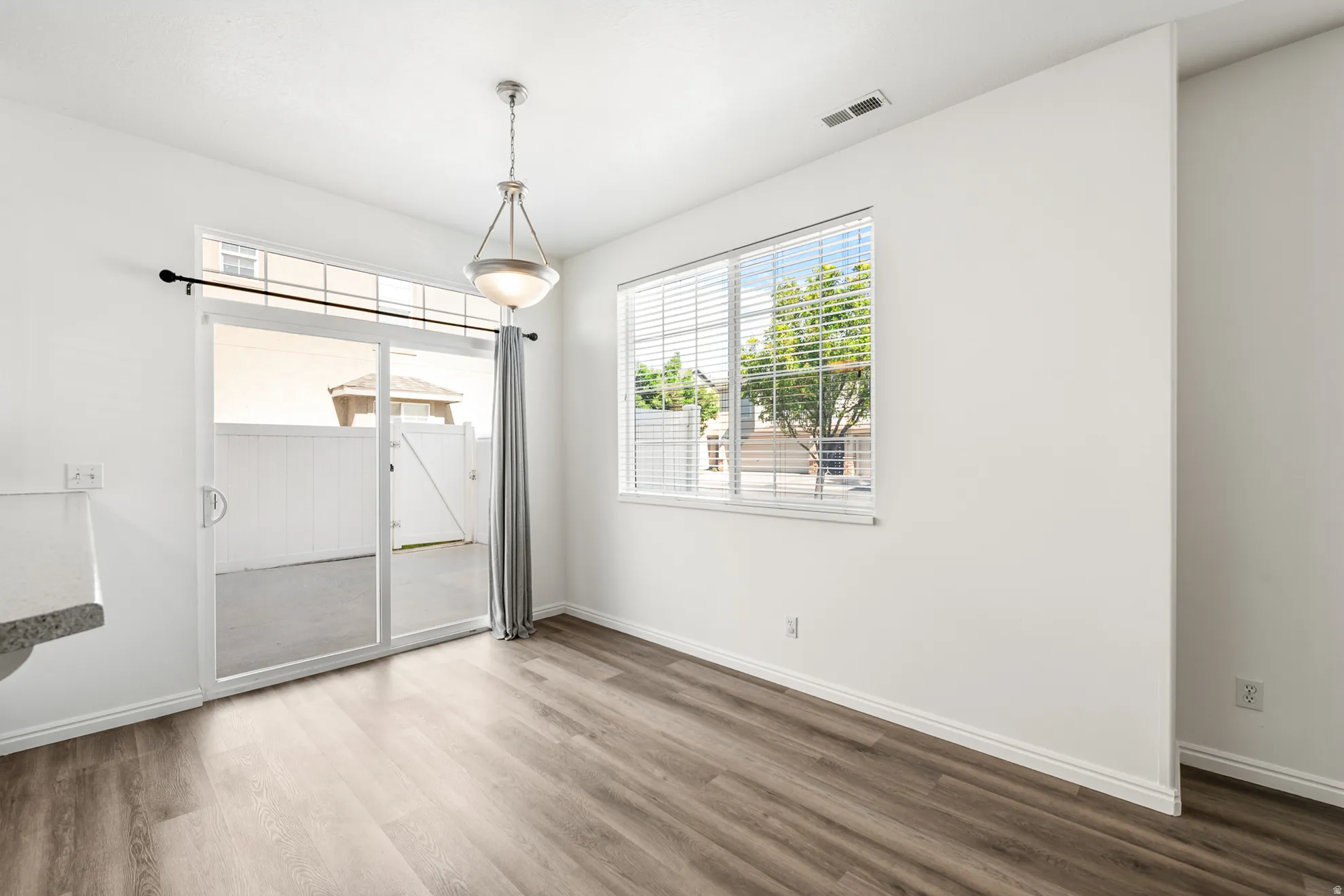 Dining area featuring wood-finish flooring, white walls, and a contemporary pendant light fixture
