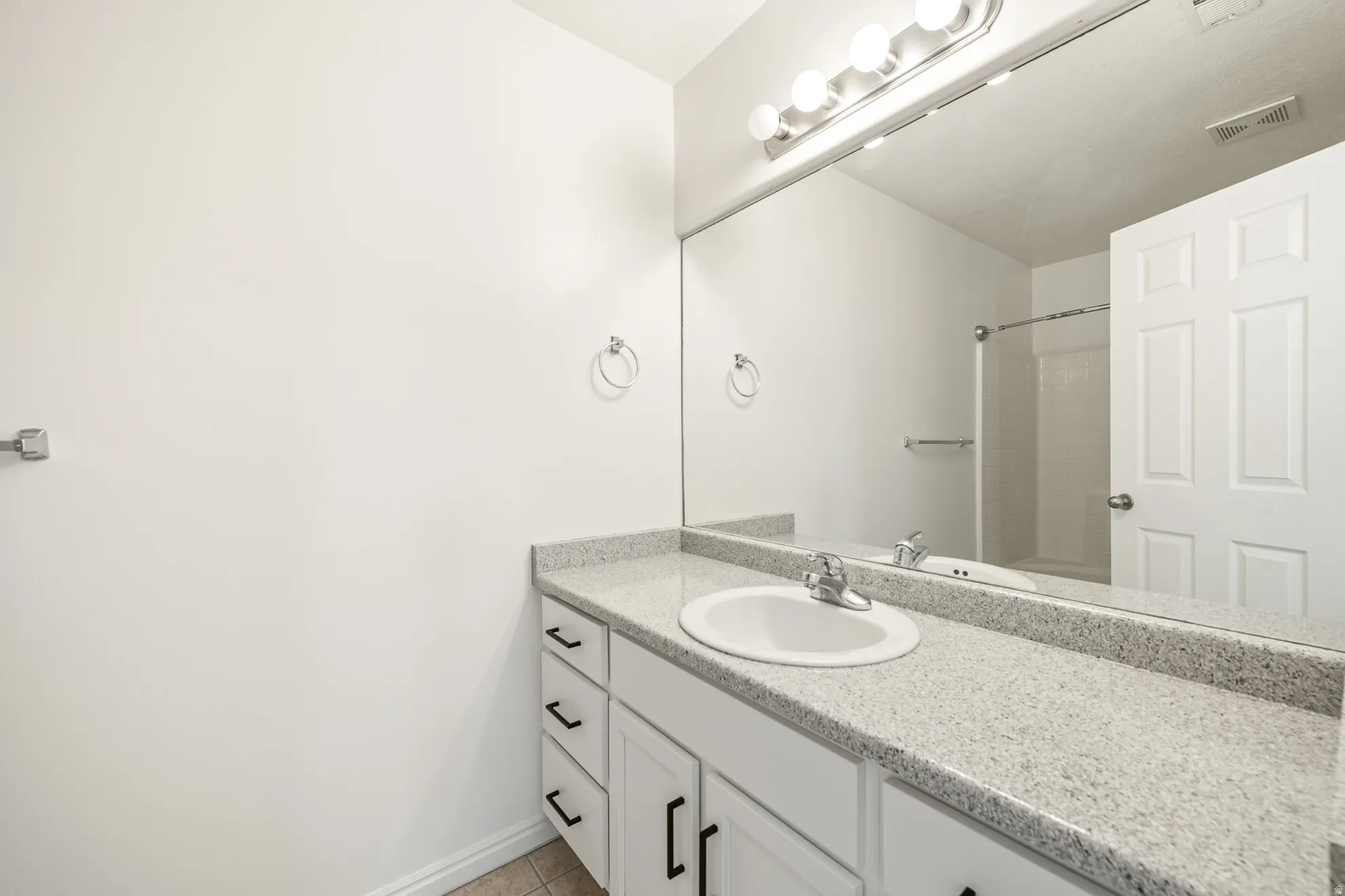 Vanity featuring a white undermount sink, chrome faucet, and speckled countertop
