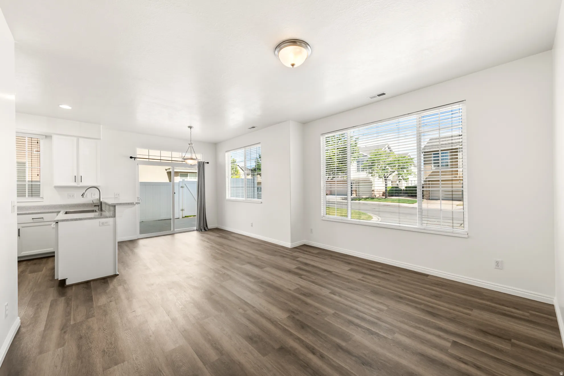Open-concept living area with wood-finish flooring, white walls, and abundant natural light from multiple windows