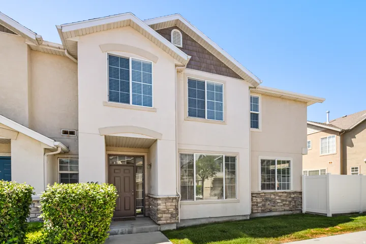 Two-story stucco exterior featuring stone accents, a covered entry, and a brown paneled front door
