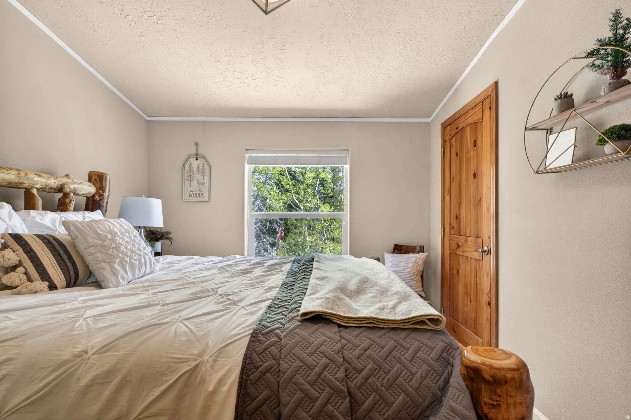 Bedroom featuring a natural wood door, a window with outdoor scenery, and a textured ceiling