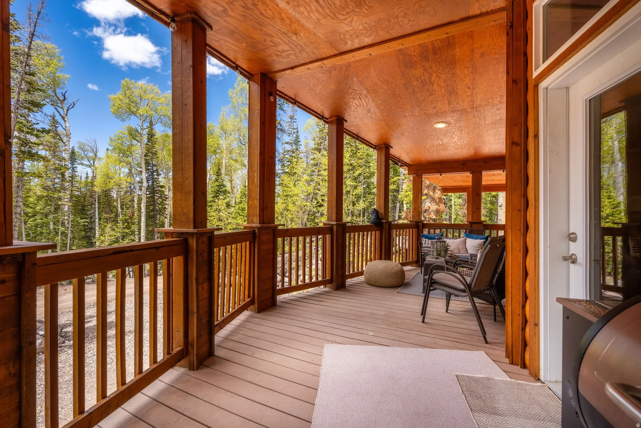 Expansive covered deck featuring natural wood posts and railings
