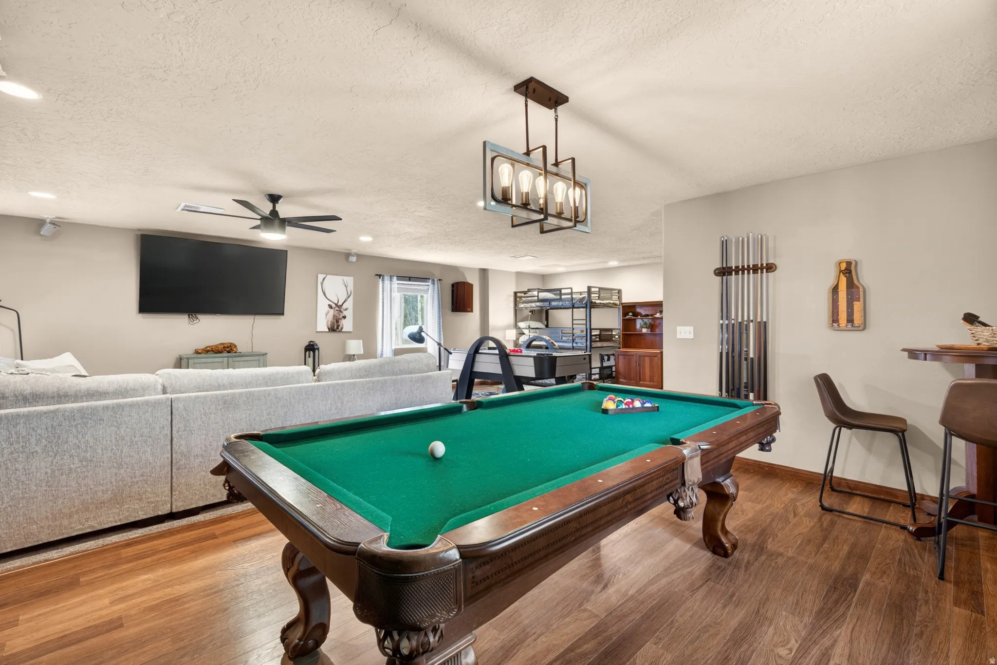 Recreation room featuring wood-finish flooring, a contemporary linear chandelier, and a built-in bar area