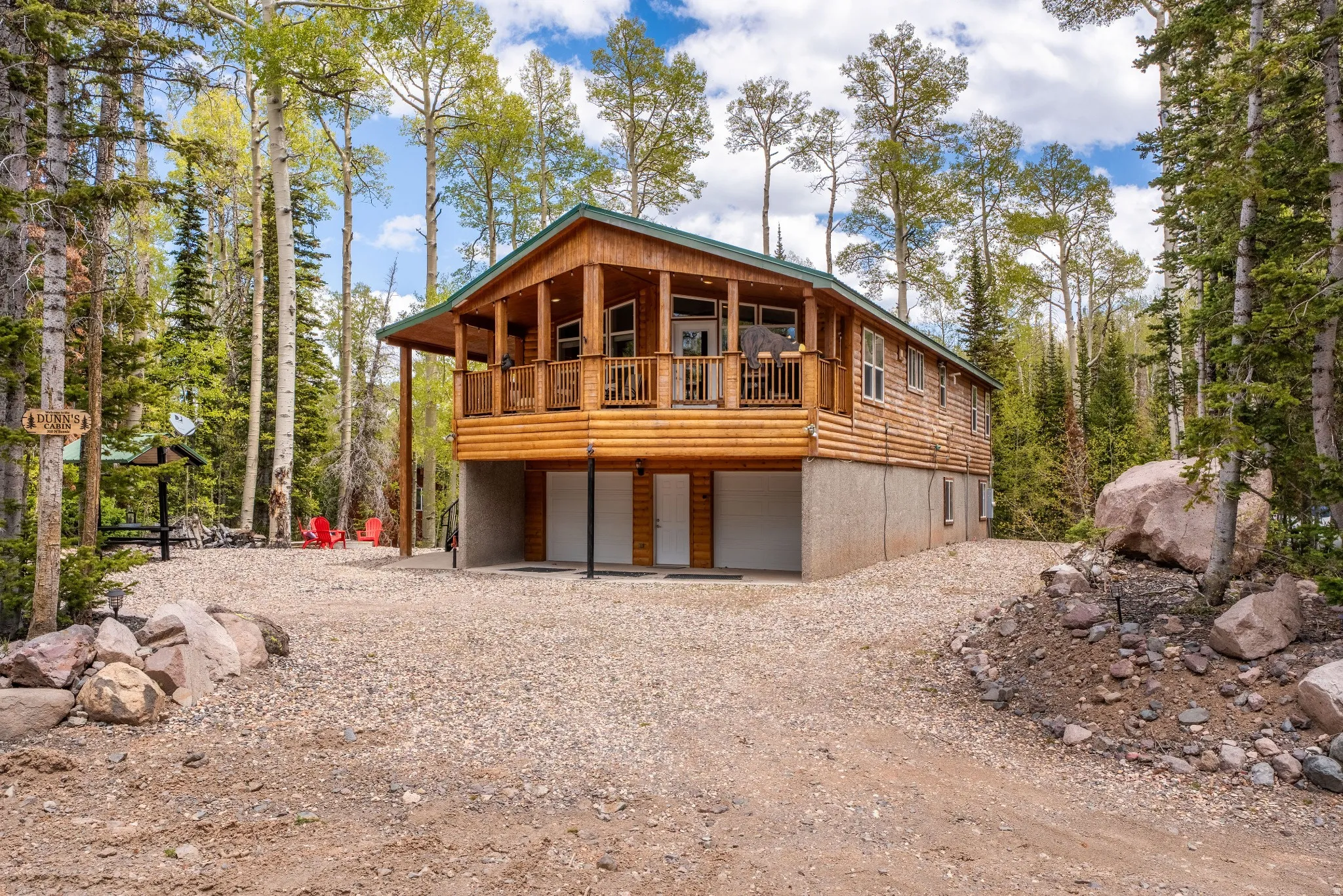 Log-sided property featuring a covered balcony, a gravel driveway, and a two-car garage