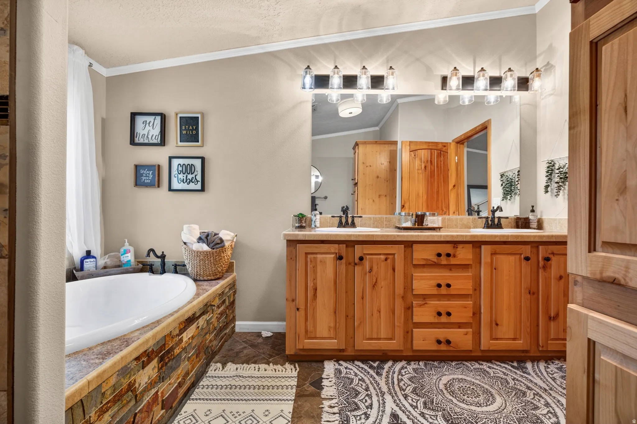 Double vanity with wood-finish cabinetry, dual sinks, and two multi-bulb light fixtures