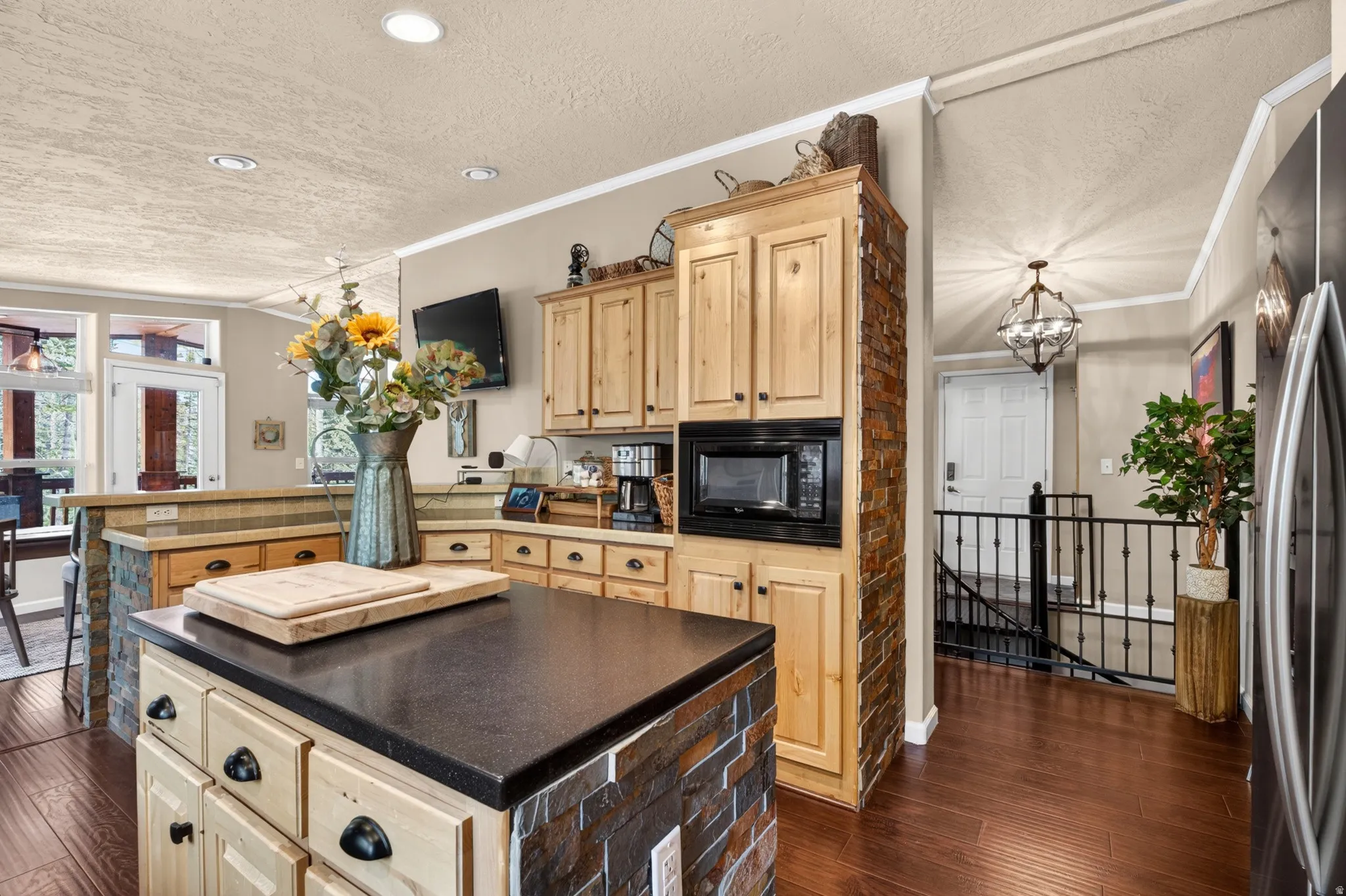 Kitchen featuring a central island with a dark countertop and stone veneer base