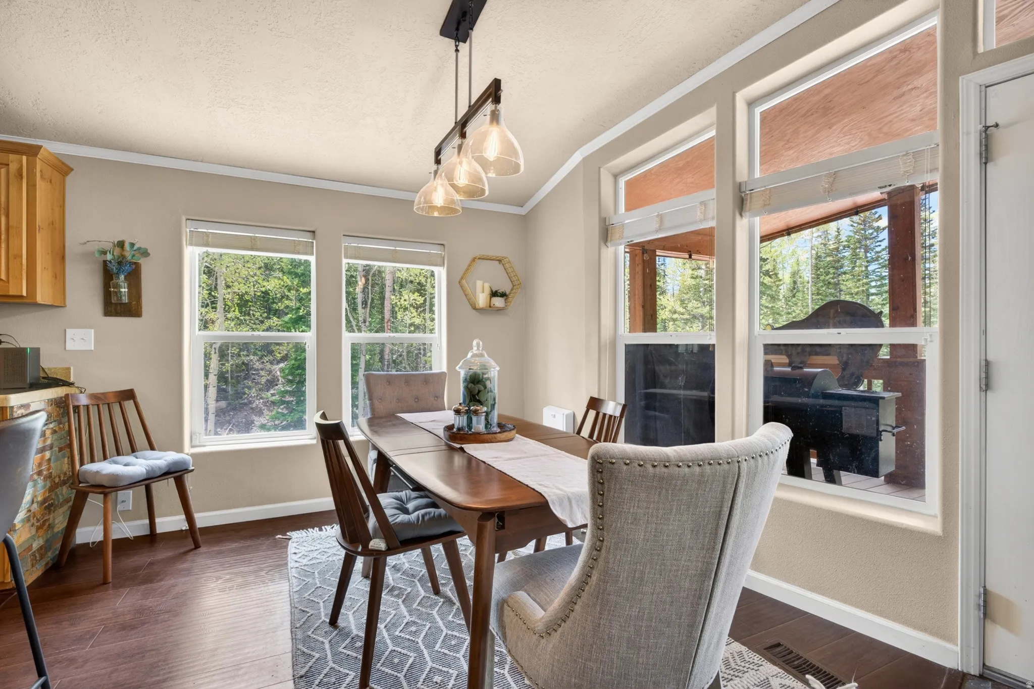 Dining area featuring wood-finish flooring, ample natural light from multiple windows, and a modern linear pendant light fixture