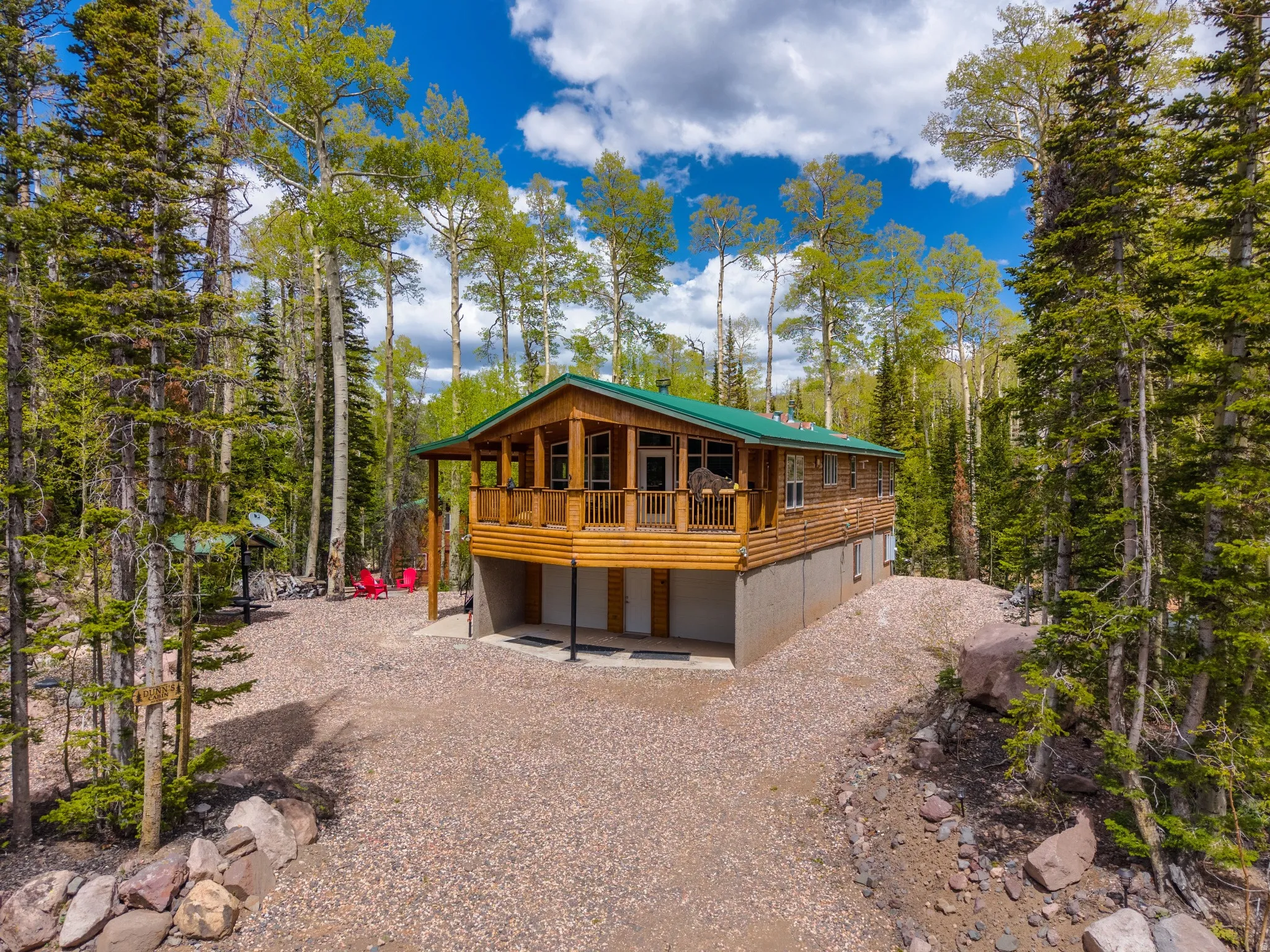 Wood-sided cabin featuring a green metal roof and an elevated porch with wood railings