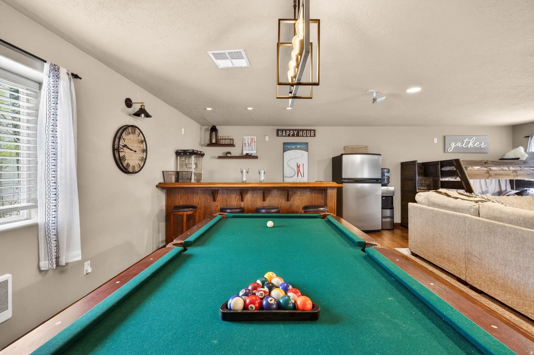 Recreation room featuring a pool table, wood-finish bar area, built-in shelving, stainless steel refrigerator, and recessed lighting