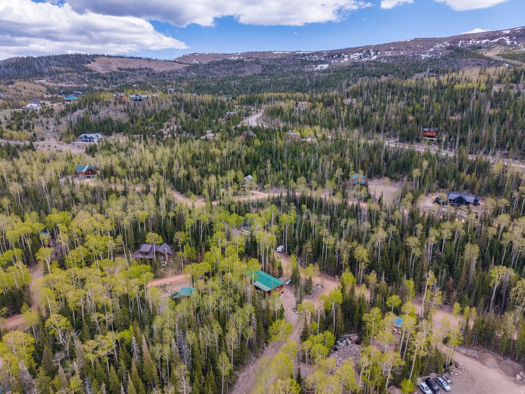 Expansive mountain property featuring varied terrain, abundant evergreen and deciduous trees, and multiple residences