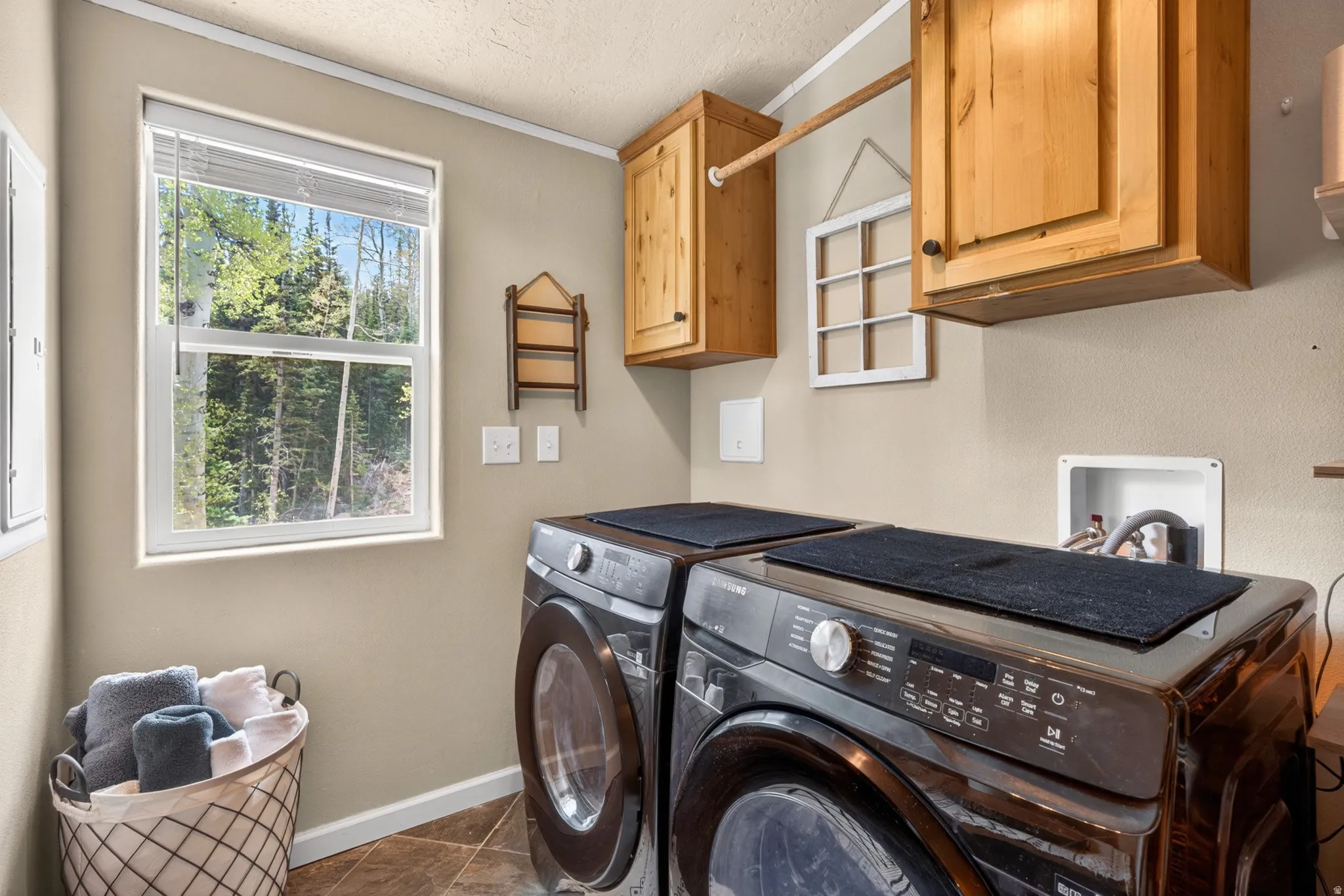 Laundry area featuring a window, wood-finish cabinetry, and tiled flooring