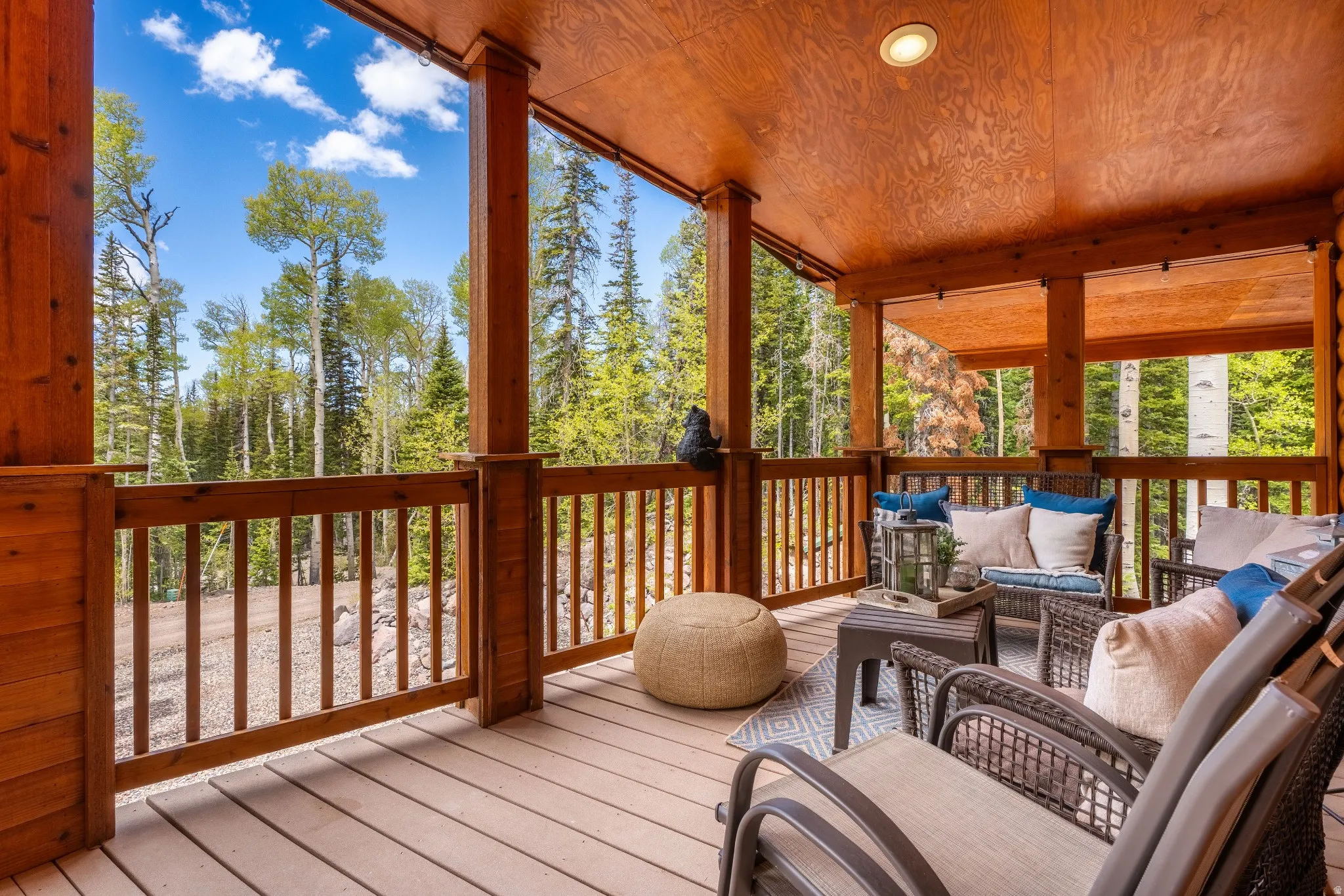 Expansive covered deck featuring a wood-finish ceiling, sturdy wood columns, and a wood-slat railing