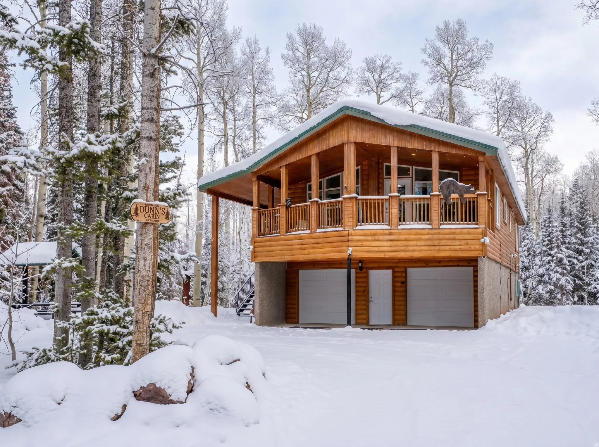 Cabin-style residence featuring a wooden exterior, a covered porch with wooden railings, and large windows