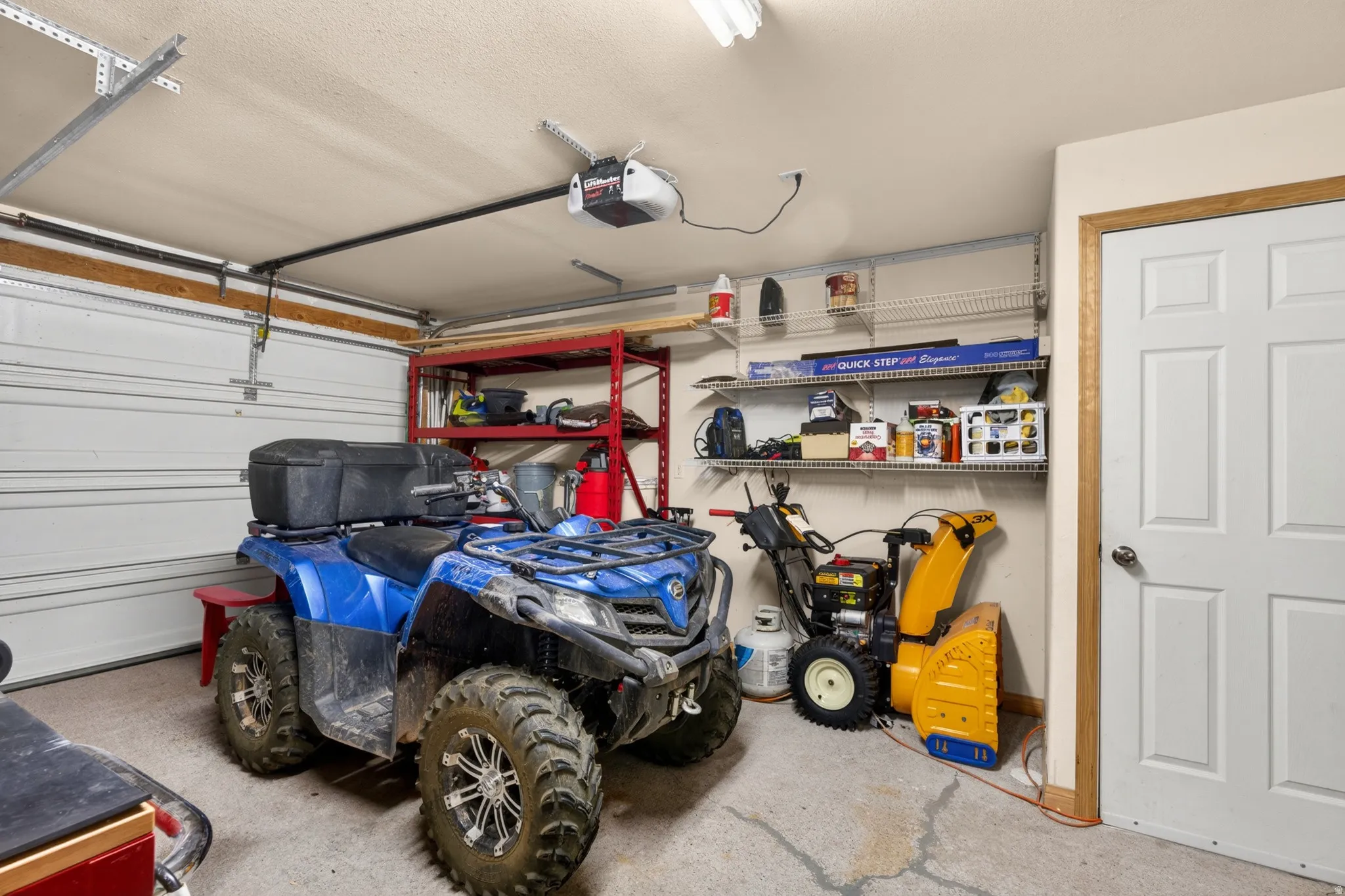 Attached garage featuring a concrete floor, automatic garage door opener, and a white paneled entry door