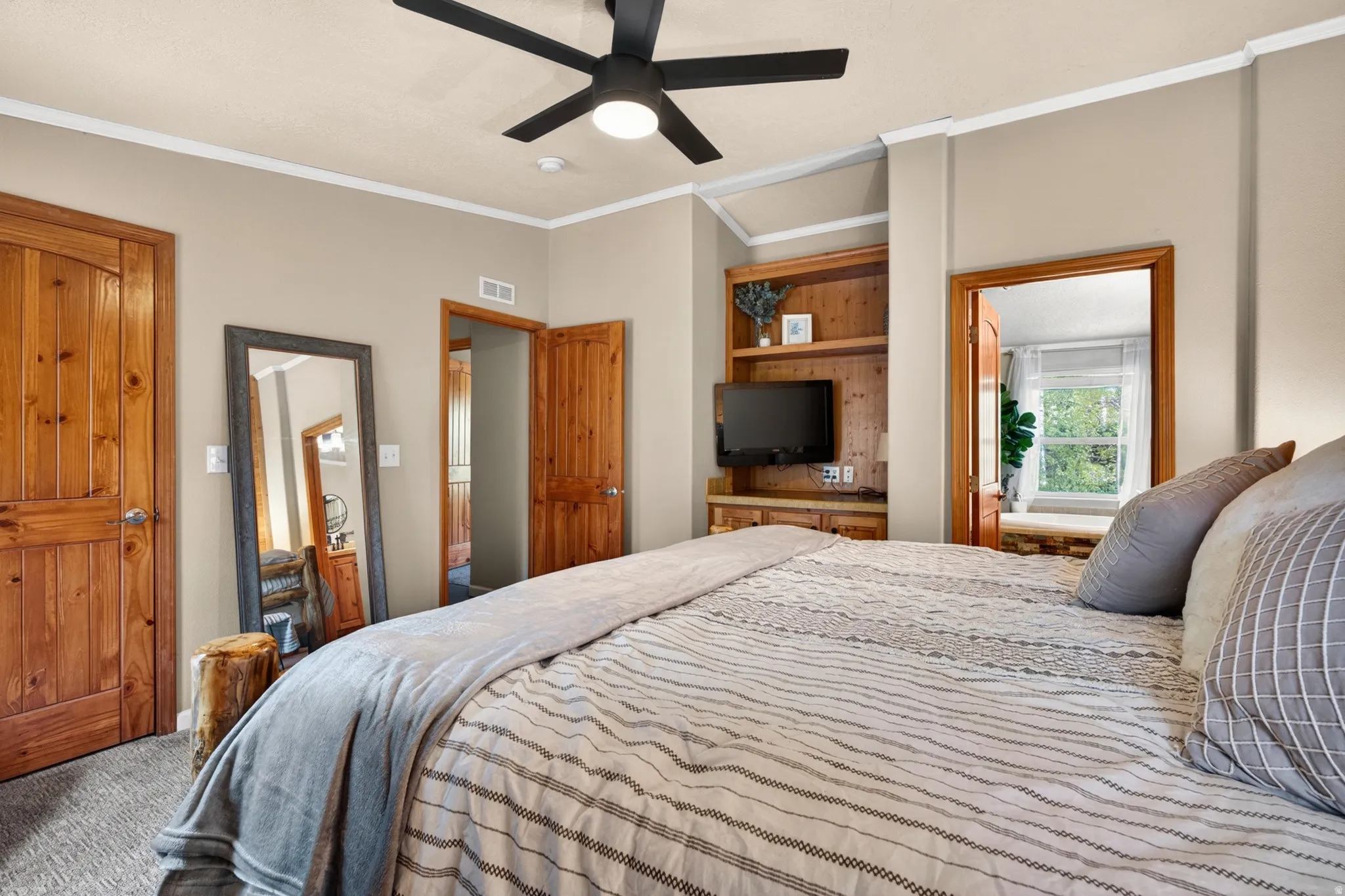 Bedroom featuring wood-finish panel doors, a ceiling fan with integrated lighting, and a built-in entertainment center with shelving