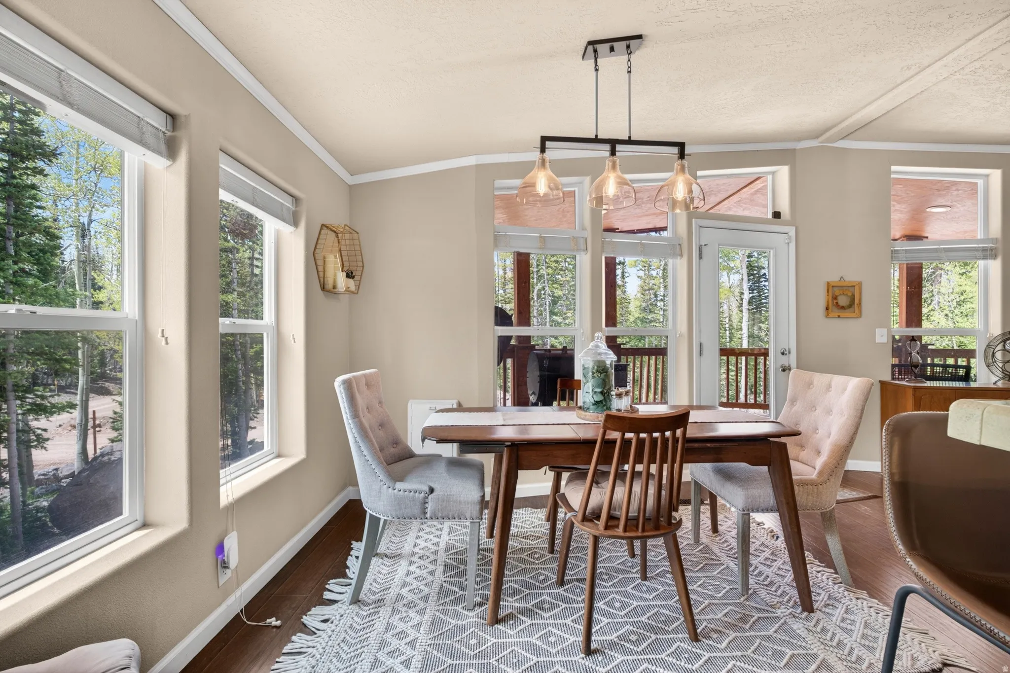 Dining area featuring ample natural light, wood-finish flooring, a contemporary ceiling light fixture, crown molding, and direct access to an outdoor space