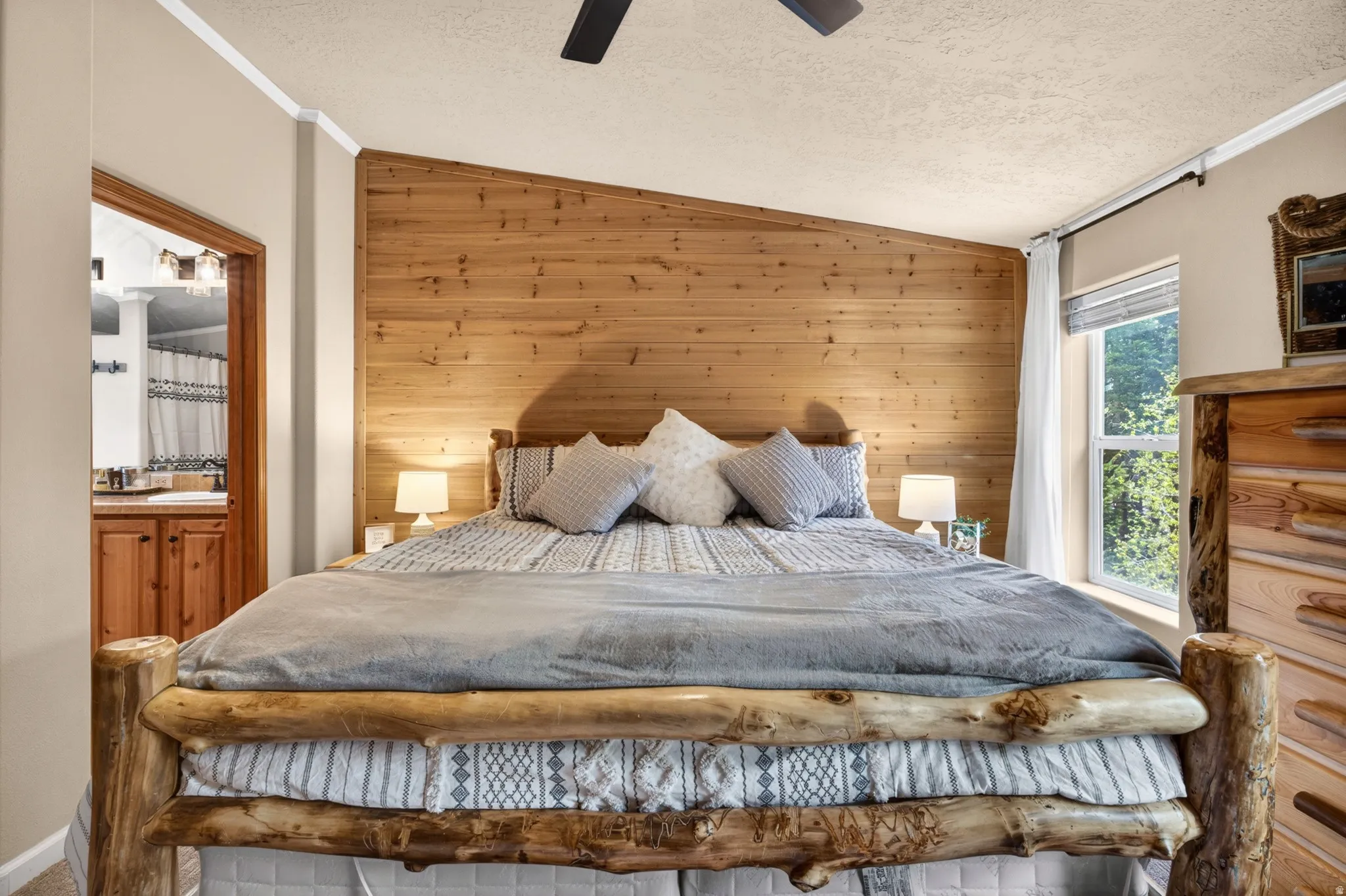 Bedroom featuring a prominent wood-panel accent wall, ceiling fan, and window with natural light
