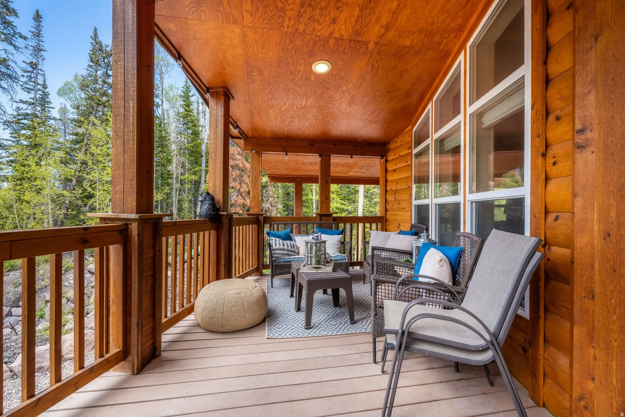 Expansive covered porch featuring wood plank flooring, log-style exterior siding, and large windows
