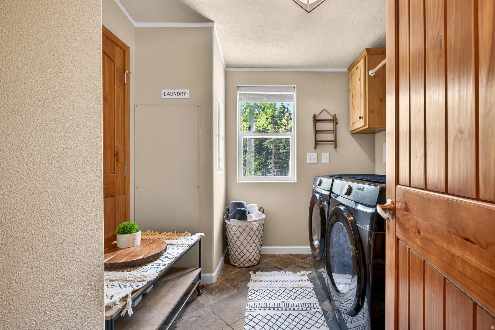 Dedicated laundry space featuring a window, wood-finish cabinetry, and tiled flooring