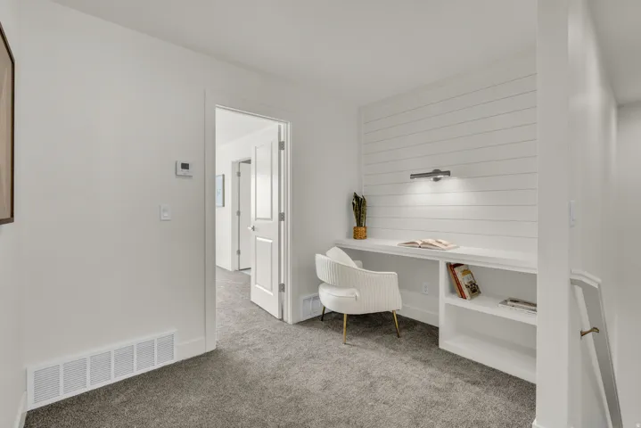 Built-in desk area featuring a shiplap accent wall, integrated task lighting, and open shelving