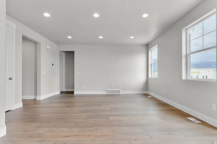 Open-concept living area featuring wood-finish flooring, recessed lighting, and multiple windows with mountain scenery