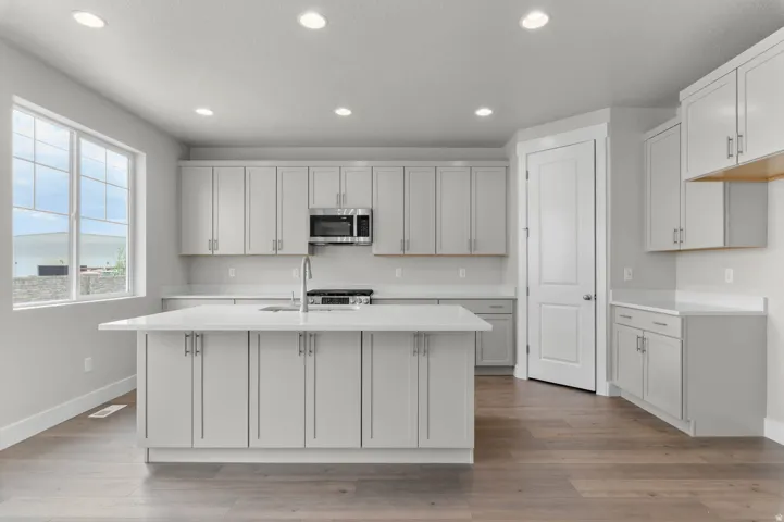Contemporary kitchen featuring an expansive center island with an undermount sink and gooseneck faucet