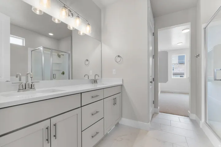 Spacious bathroom featuring a double vanity with light gray cabinetry, brushed nickel hardware, and a white countertop