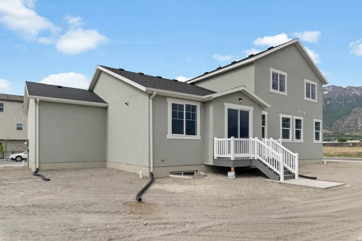 Contemporary exterior with light gray stucco siding, multiple windows with white trim, and a black shingle roof