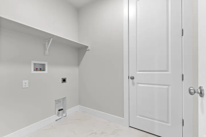 Utility room with a white shelving unit, light gray walls, and white baseboards