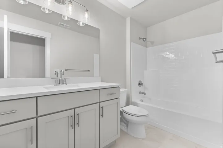 Bathroom featuring a light gray vanity with an integrated sink, polished chrome faucet, and expansive mirror