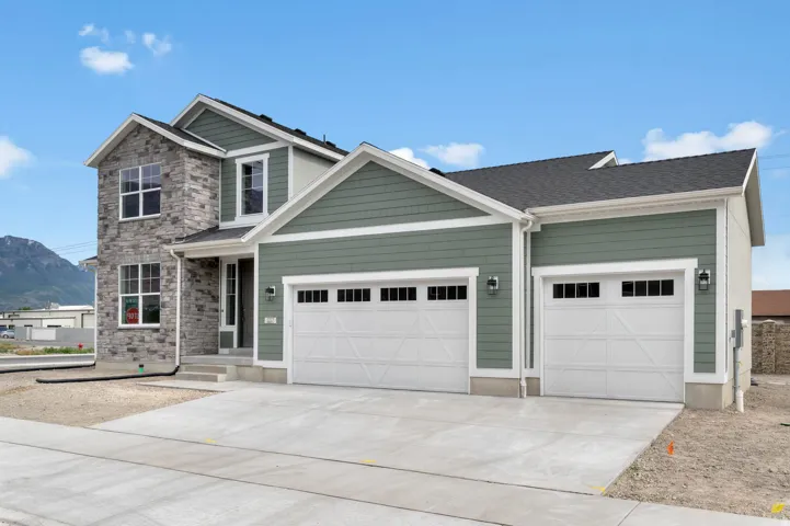 Contemporary two-story exterior featuring a stone and siding facade, a two-car garage with carriage-style doors, and a concrete driveway