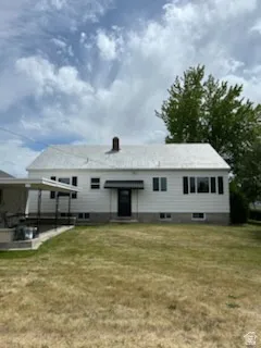 White exterior with dark shutters, a covered entry, and a side patio with a metal awning