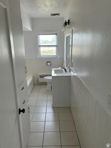 Ceramic tile flooring features in this bathroom, complemented by white wall tile wainscoting
