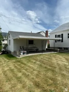 Rear exterior featuring a covered concrete patio, white siding, and a dark shingle roof