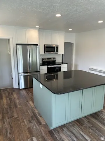 Kitchen featuring a central island with a dark countertop and sage green cabinetry