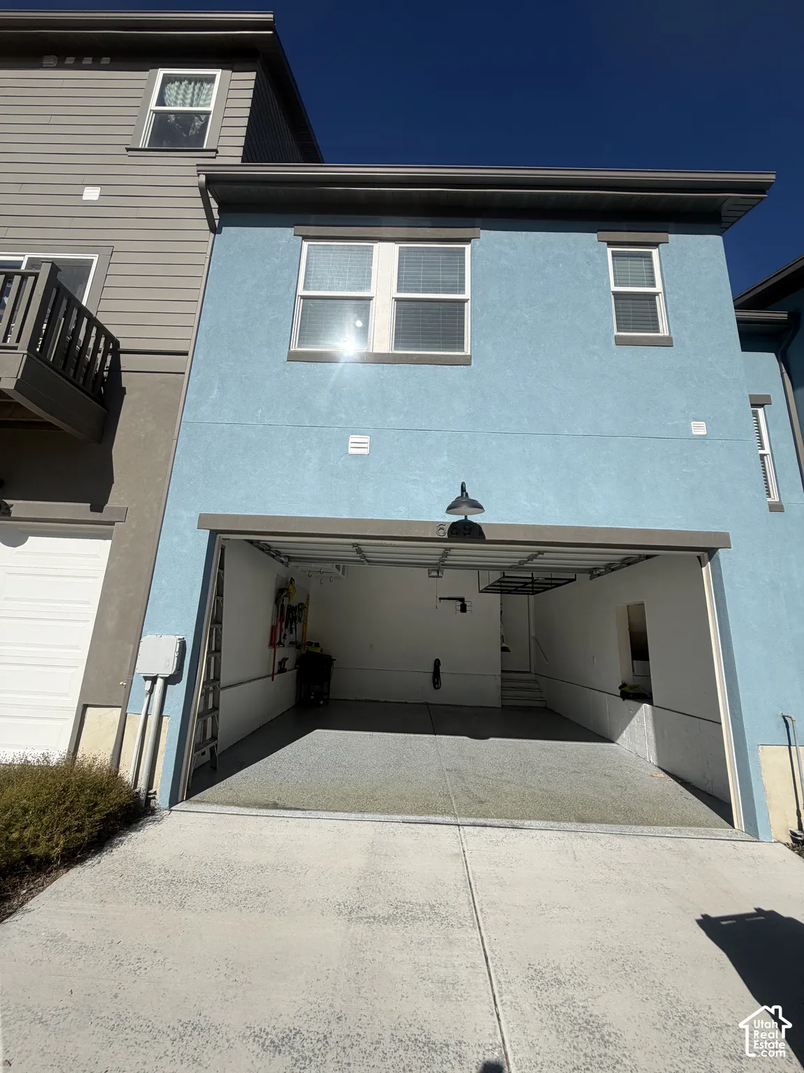 Stucco exterior featuring an attached two-car garage with epoxy-coated flooring and exterior gooseneck lighting