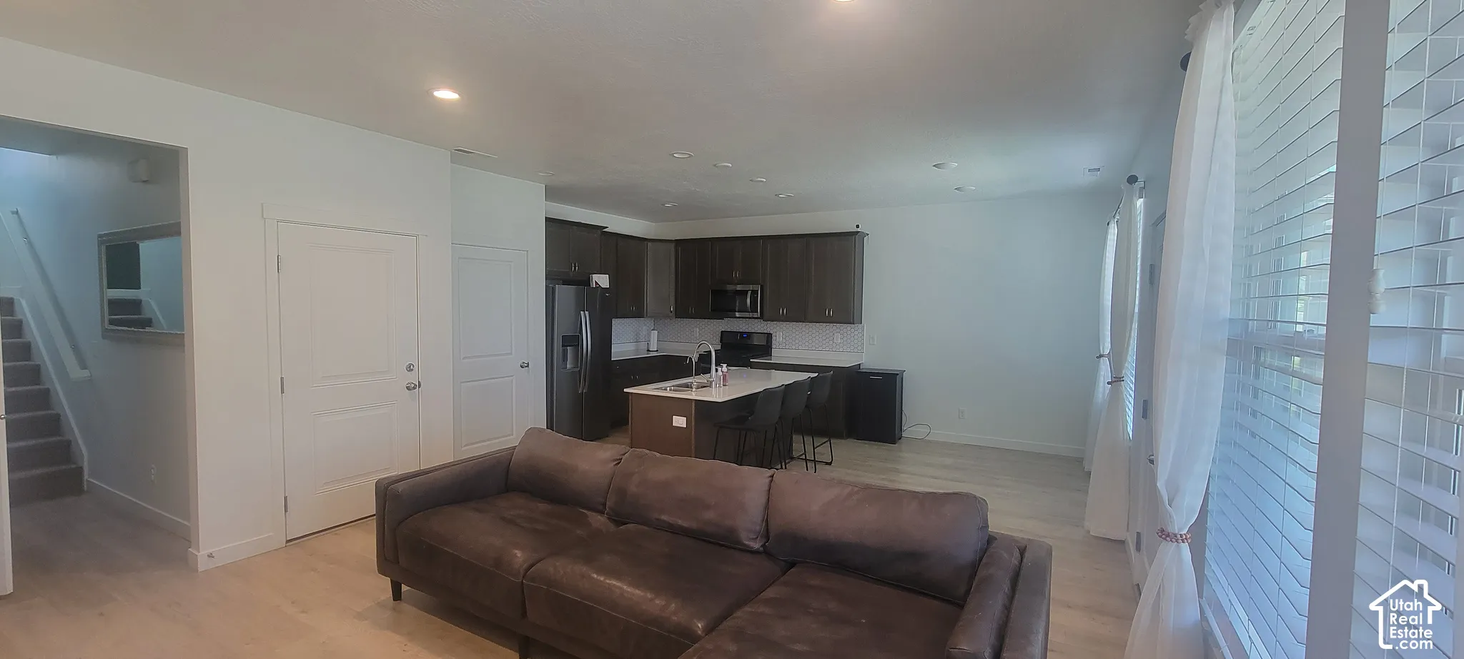 Open-concept living area featuring light wood-finish flooring, recessed lighting, and white walls