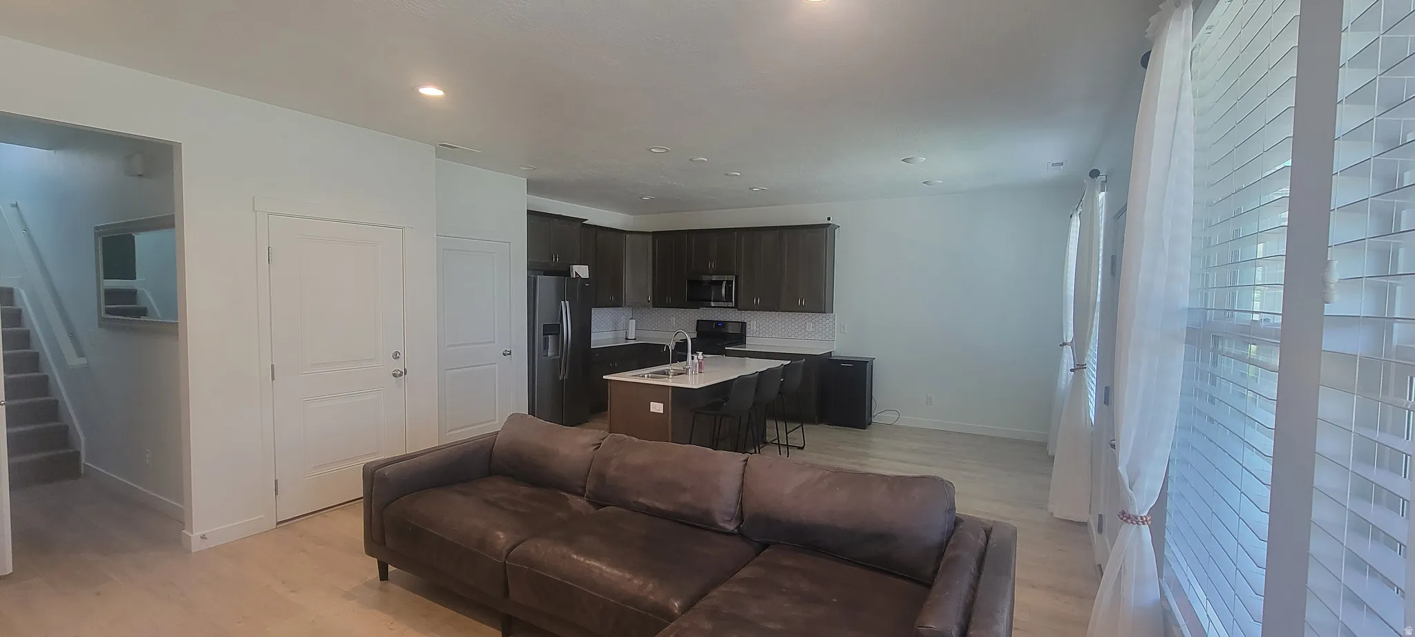 Open-concept living area featuring light wood-finish flooring, recessed lighting, and white walls