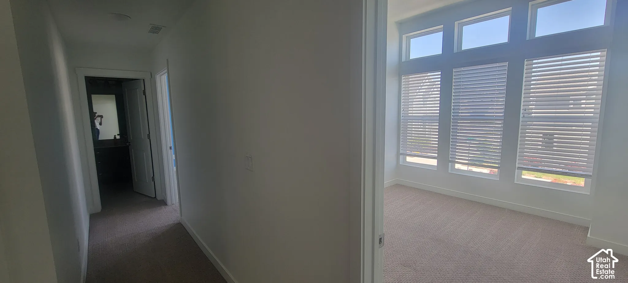 Hallway and bedroom 1 Bright interior room featuring a series of tall windows with horizontal blinds