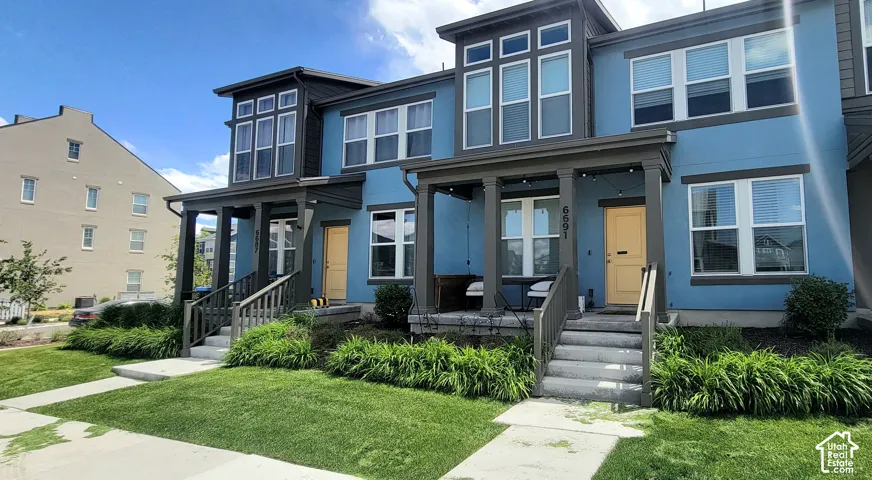 Modern townhome exterior with a distinctive blue facade, contrasting charcoal trim, and a bright yellow front door