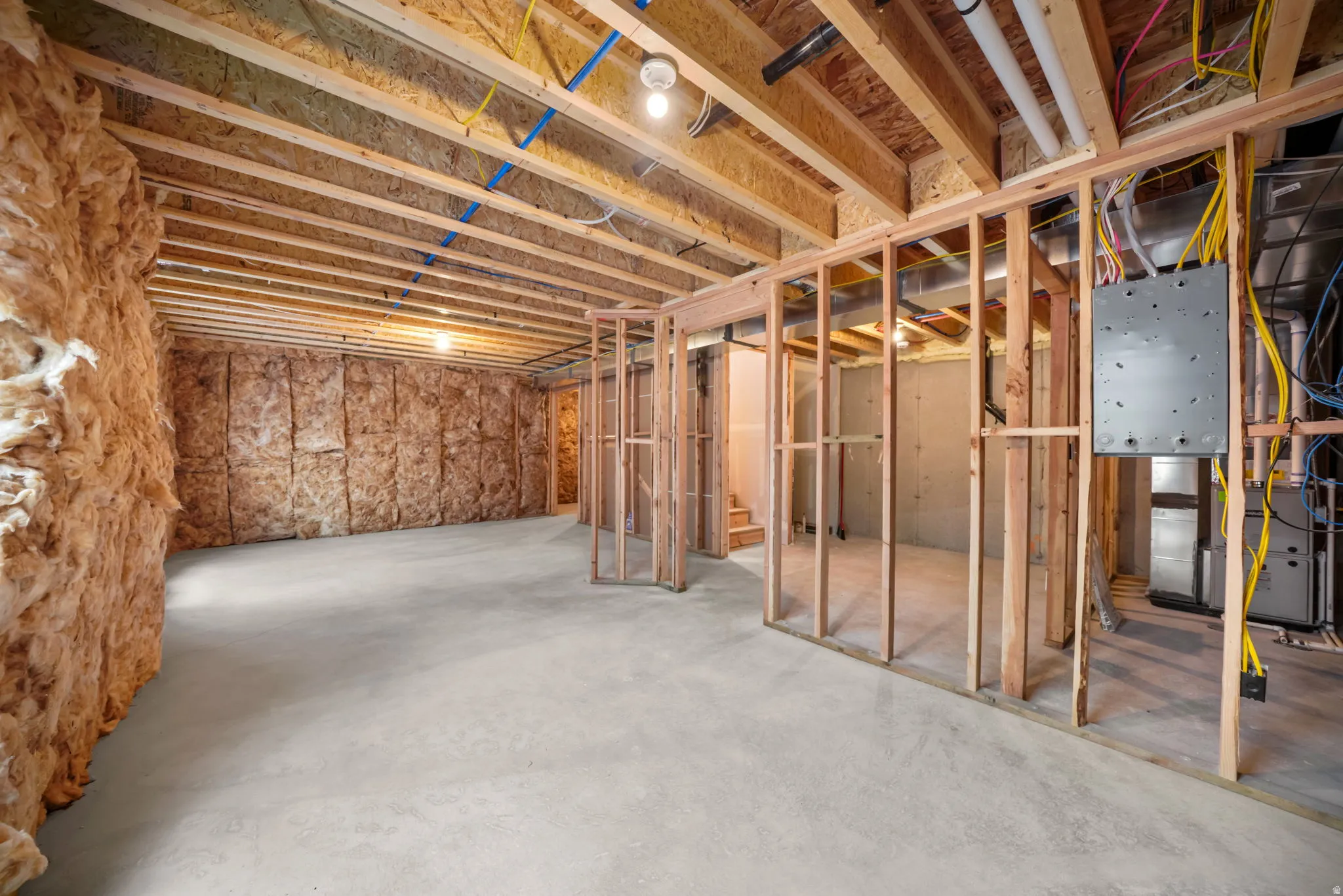 Unfinished lower level featuring exposed wood framing, concrete flooring, and insulated perimeter walls