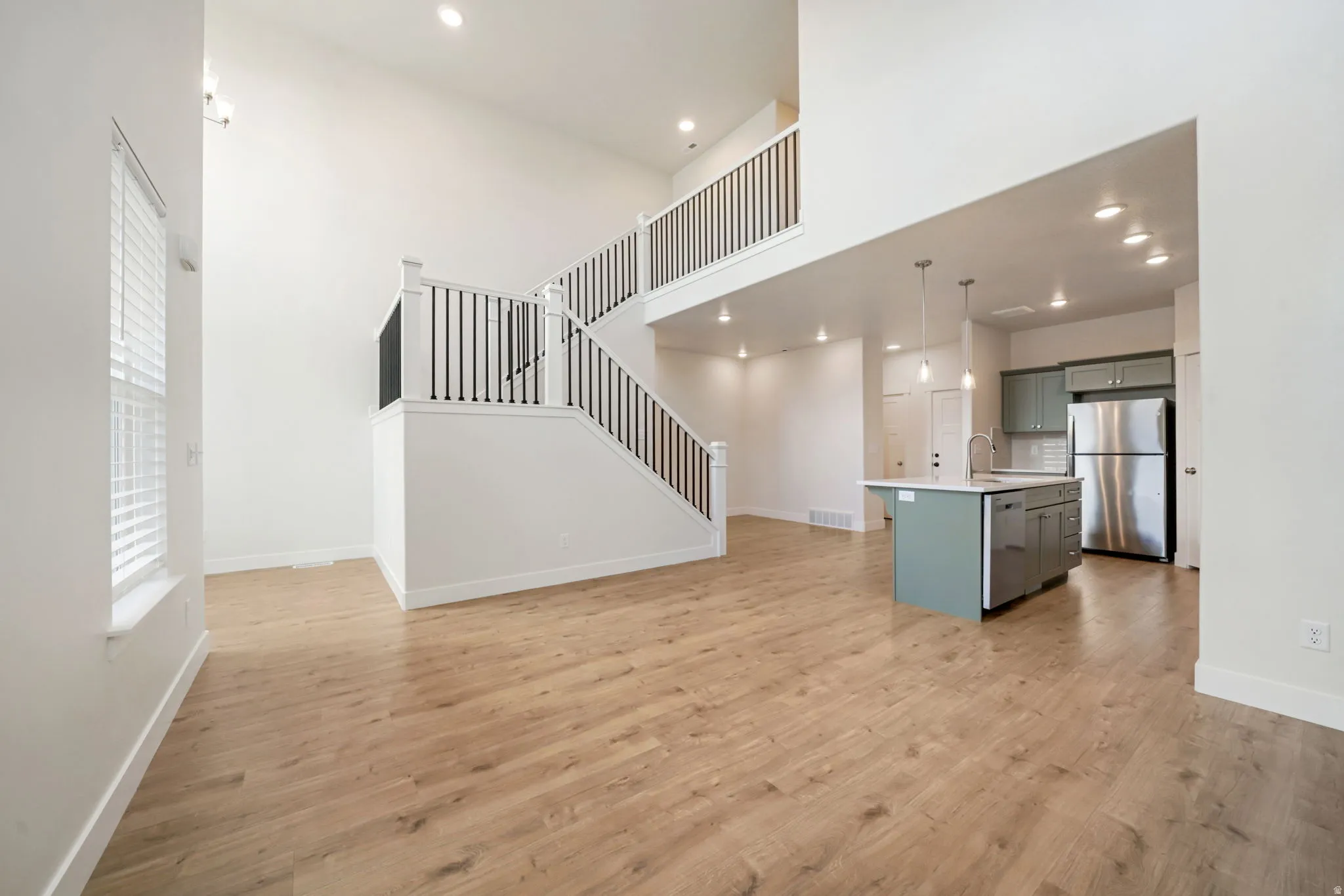 Open-concept living space featuring wood-finish flooring, a two-story ceiling, and a modern kitchen