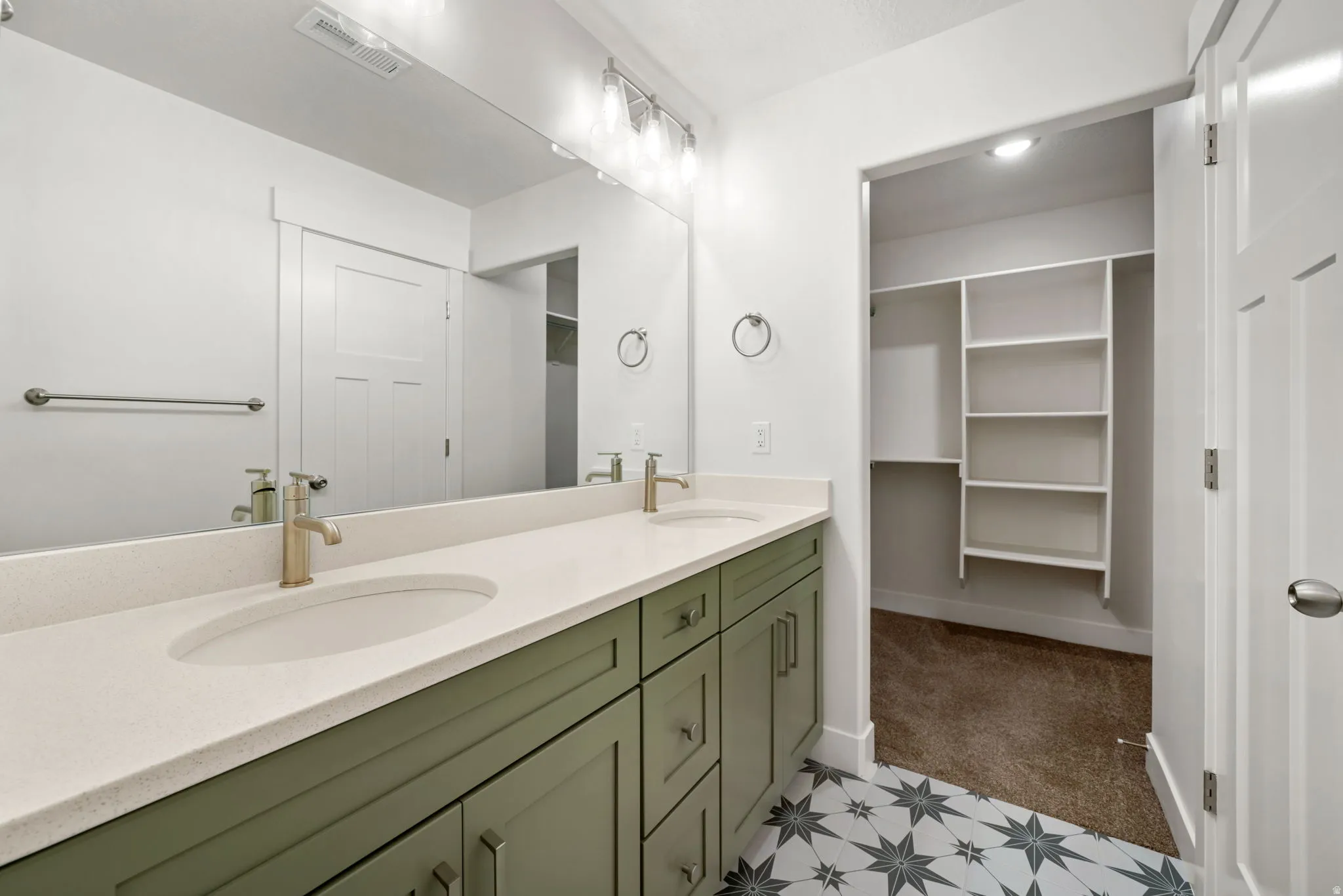 Dual vanity featuring green cabinetry, light-toned countertops, and gold-finish fixtures